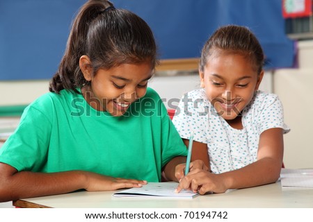 Cheerful school girls in class learning together