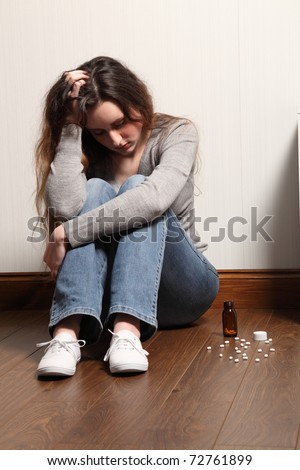 Teenage girl sitting on the floor at home, looking scared and frightened.