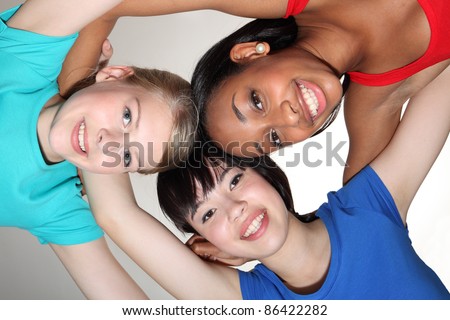 Big smiles in fun team group huddle by mixed race african american, oriental Japanese and blonde caucasian teenage school student girl friends looking down to camera.
