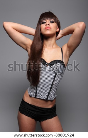 Beautiful sexy young mixed race lingerie model woman with long brown hair, wearing black and white bustier style corset top and black boy short knickers.