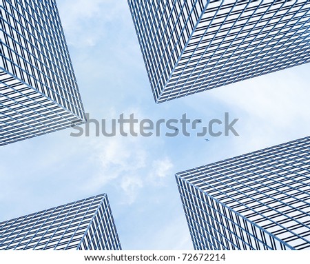 Designed futuristic background - three small private planes rising up above four giant modern business buildings in front of cloudy blue sky