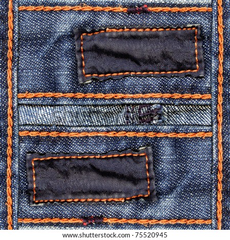 Designed blue jeans background with two blank dark cotton labels and orange seams\' threads