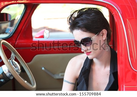 Sexy female beauty sitting in a classic car outside.