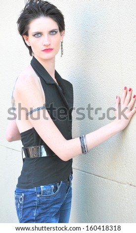 Female biker posing against a wall outside.