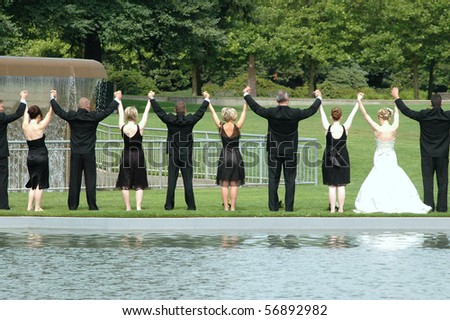 Wedding party posing in a park outdoors.