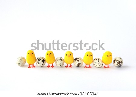 Five little decorative chickens in a line next to eggs