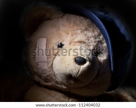Crying Teddy Bear wearing blue baseball cap hiding in the shadows.  May be bully, may be victim, may be in pain or anguish.