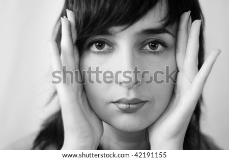 Beautiful woman face greyscale close-up framing her face with her hands
