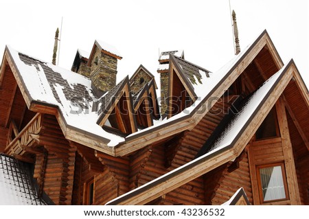Roof of the wooden cottage with chimneys and dormers covered with snow