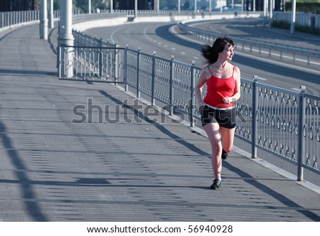 Woman jogging on empty highway on industrial background