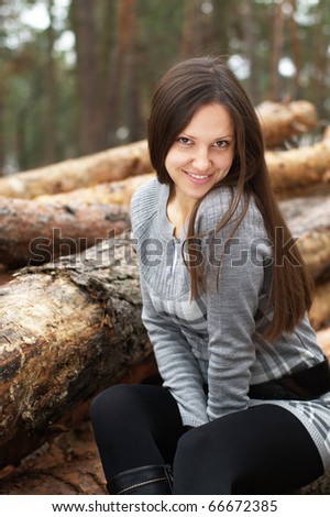 Young woman outdoors with dog by log pack