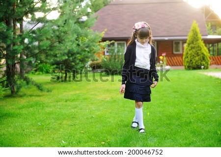 Adorable elegant  kid girl in navy and rose  school uniform staying on the lawn after school