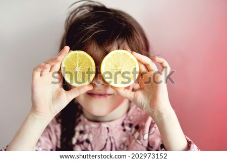 Art portrait of little girl with juice lemons as eyes: rose tone
