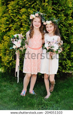 Two beauty flower  kid girls in elegant dresses with flowers wreath on the heads and elegant bouquets