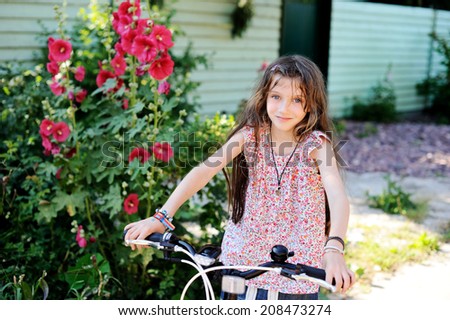 Adorable kid girl on her bike outside in the warm summer evening