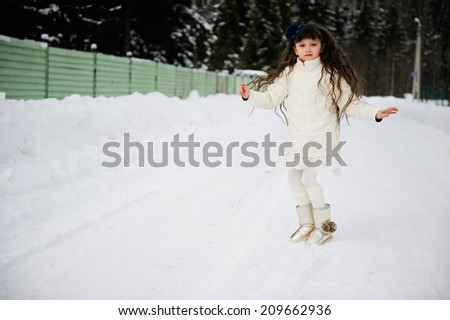 Adorable little girl with long hair in white clothes has fun outdoor at the winter day
