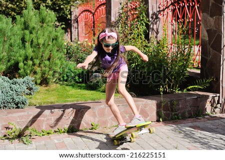 Cute school aged girl riding skateboard in the park