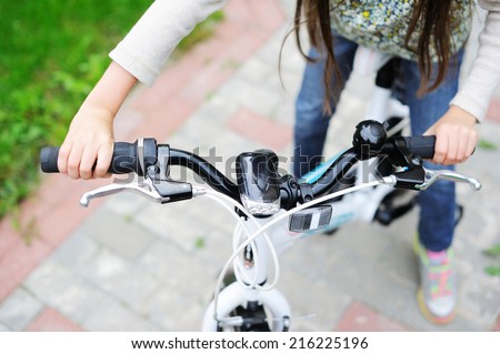 Kid girl\'s hands on the bicycle outdoors