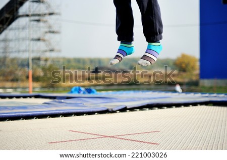 View of the young boy feet in stripe socks jumps on the trmpoline outside during acrobatics practice