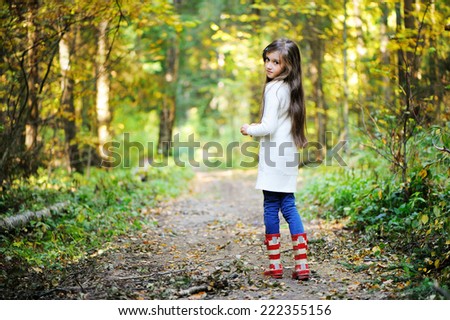 Beauty school aged brunette girl in white sweater and rain boots in the beauty autumn forest