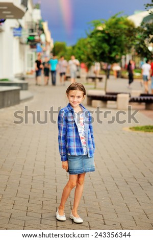 Adorable kid girl in the fancy clothes on the real rainbow background in the city street