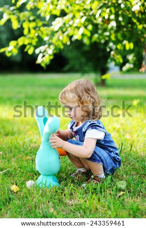 Cute little girl with a bunny rabbit  at green grass background
