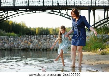 Family portrait of a smiling and cheerful mother and daughter having fun near th river