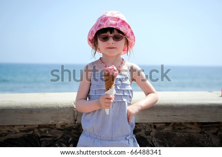 Small girl in glasses and sun hat on sea background with ice cream