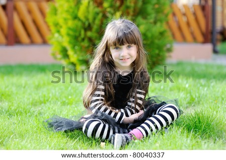 Adorable little girl with very long brunette hair in halloween outfit in the garden