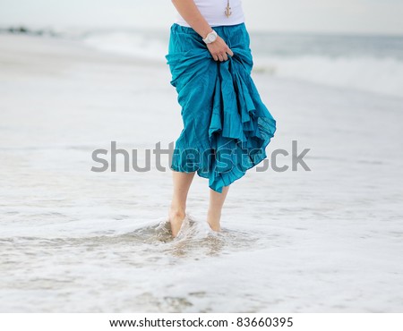 Young woman\'s feet washed by ocean waves
