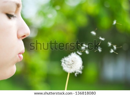 Close up ow woman blowing dandelion flower