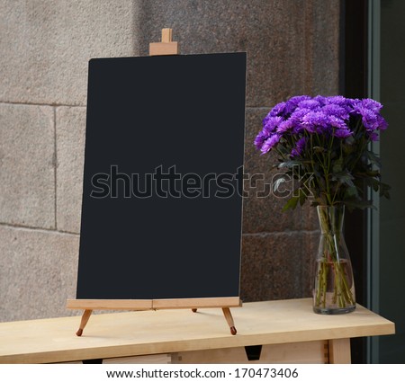 Wooden board for restaurant menu with empty space to add text standing at restaurant entrance with flower pot