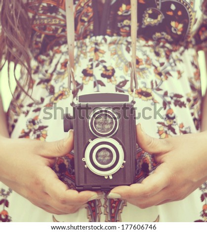 Retro image of woman hands holding vintage camera outdoors