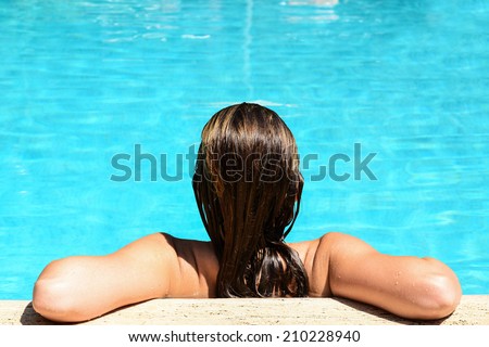 Back view of relaxed woman in swimming pool with blue water