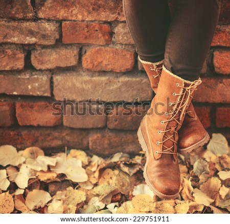 Conceptual image of legs in boots on the autumn leaves - Walking in nature