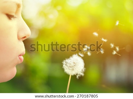 Close up ow woman blowing dandelion flower