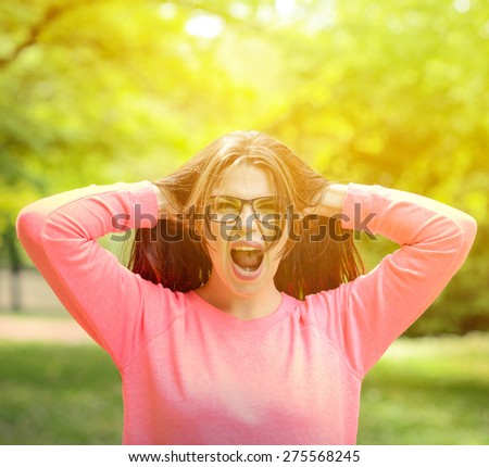 Scream - Beautiful young woman screaming and pulling hair outdoors