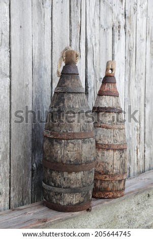 Antique weathered wooden fishing net markers with metal hoops, standing at a plank at boathouse wall. Photographed in Helgeland archipelago, Nordland, Norway.