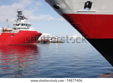 View from between red ships, a cruise ship and a supply ship