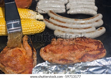 Brushing barbecue sauce on meat on gas grill