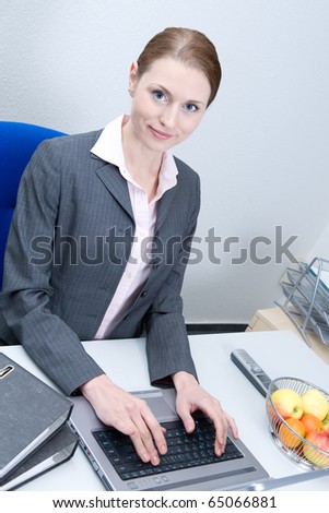 Business woman typing on laptop computer and looking at camera