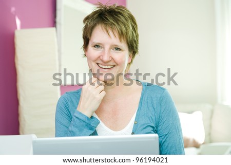 Portrait of happy middle age woman with notebook at home smiling at camera