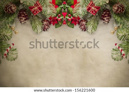A Christmas border at top of frame consisting of artificial pine tree fronds and decorative ornaments, framing top and sides of grungy parchment.