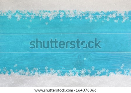 Christmas snow and snowflakes border at top and bottom of light, bright blue wood planking.
