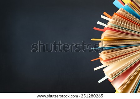 A rotating card index, filled with cards and divided with multicoloured tabs. cropped at right side of frame.  A black chalkboard background provides copy space to the left. Stockfoto © 