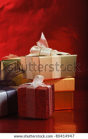 A selection of gift packages, tied with ribbons, against a foil red background.  Vertical (portrait) orientation.