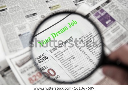 Magnifying glass over a newspaper classified section, with Your Dream Job text
