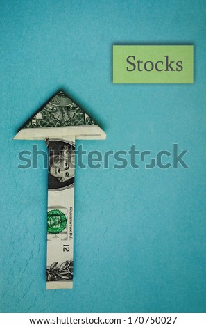 origami dollar arrow pointing up with Stocks text, on blue
