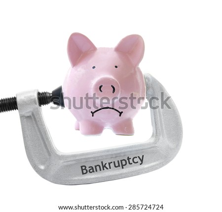 Sad piggy bank being squeezed in a Bankruptcy vice, on white