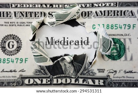 Hole torn in a dollar bill with medicaid text